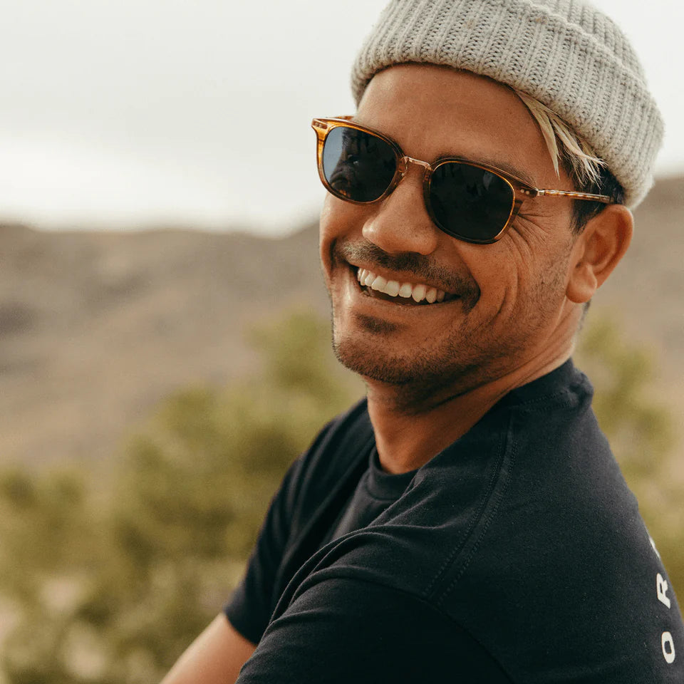 Man wearing sunglasses and a beanie with a mountainous background